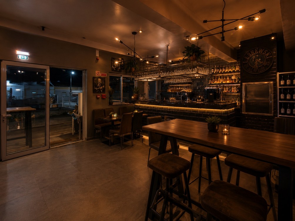 Approved main-bar concept with warm lighting, blackened metal and timber tables at the Candidate A reference property
